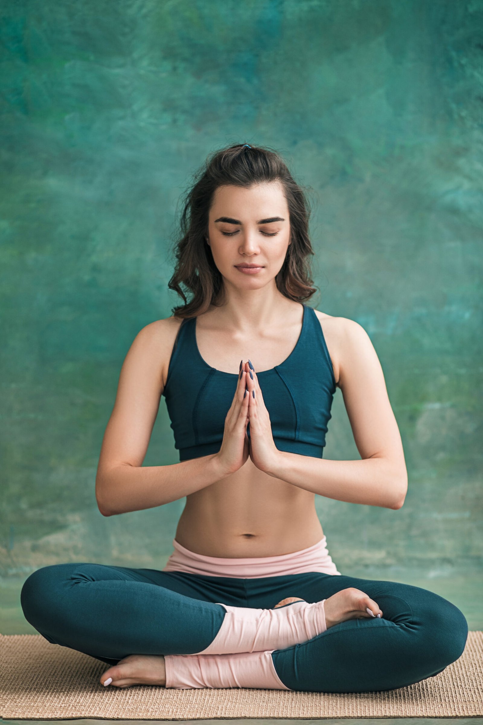 Studio shot of a young fit woman doing yoga exercises on green background